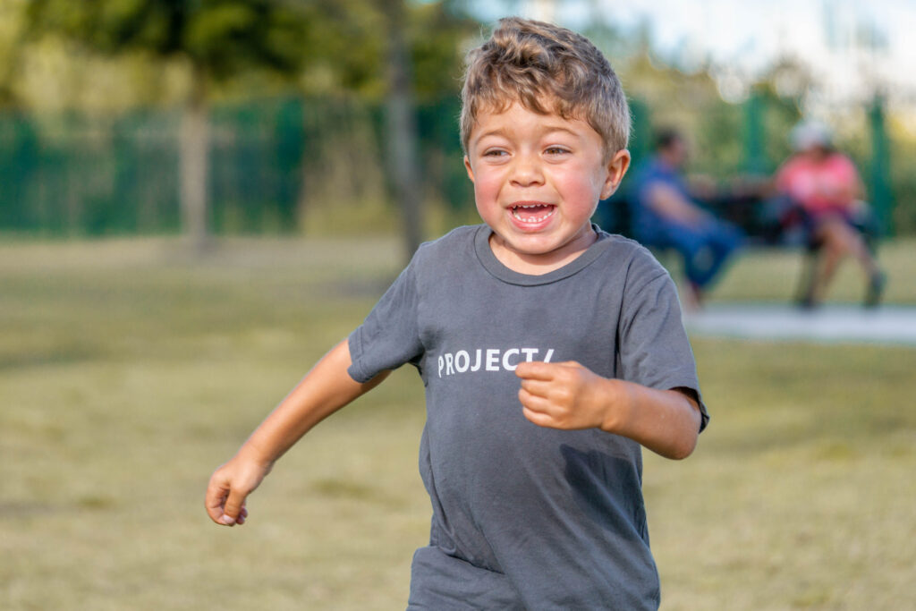Child with Hunter's Syndrome happy while running towards the camera during Petland puppy playdate.