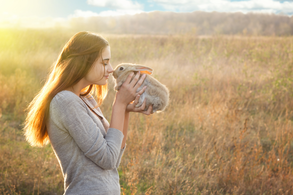 Petland Pembroke Pines picture of a girl holding her pet rabbit in a field.