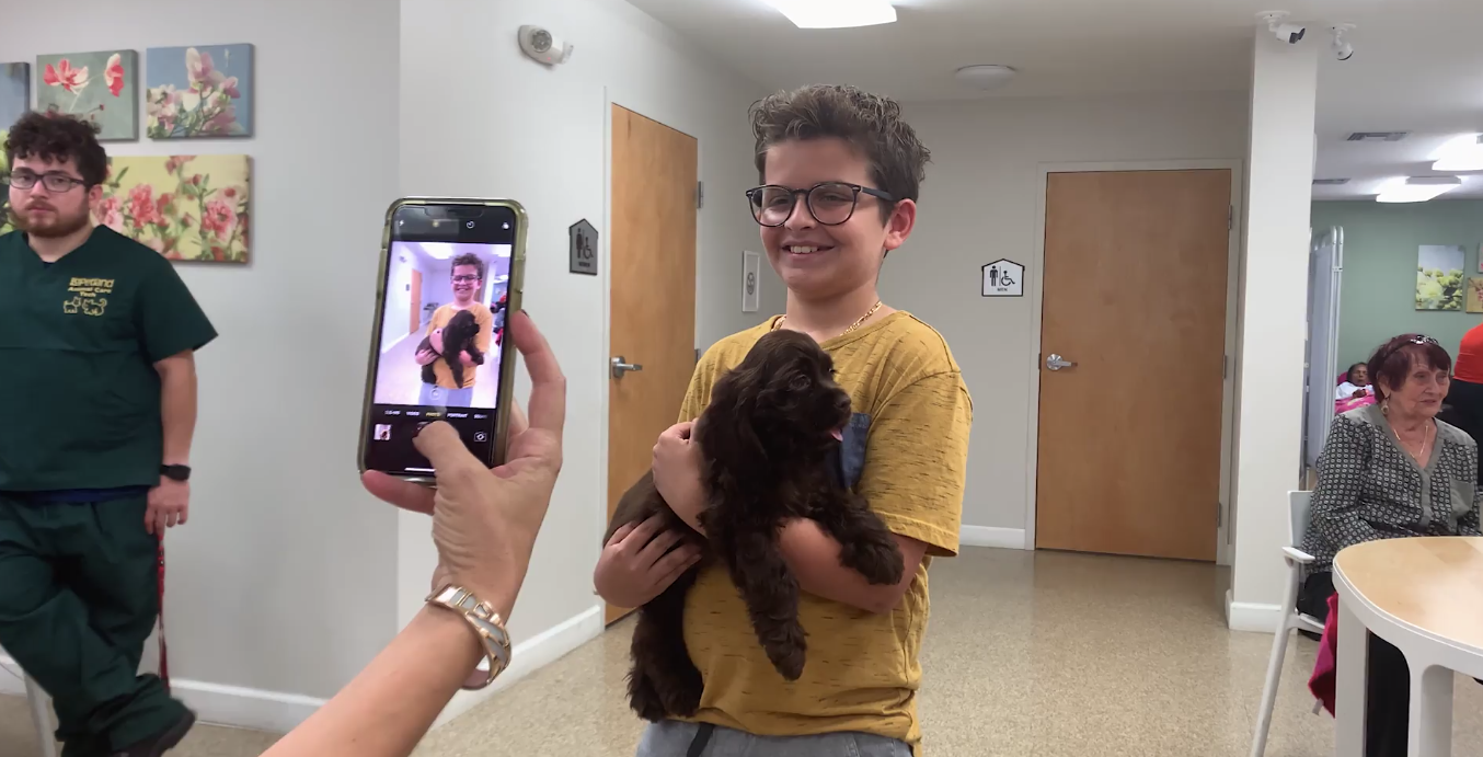 Petland Pembroke Pines picture of child holding a cute petland puppy and taking a selfie photo.