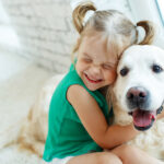 Petland Pembroke Pines picture of little girl hugging a cute Golden Retriever puppy.