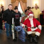 Petland Pembroke Pines picture of Miami Power Team child and Petland owner posing with Santa Claus at community event.