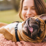 A happy puppy being held by their owner while spending a day at the park.