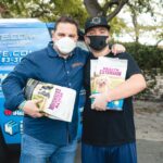 Petland Pembroke Pines picture of Petland owner, Luis Marquez and a pet owner holding bags of dog food and standing in front of a blue van.