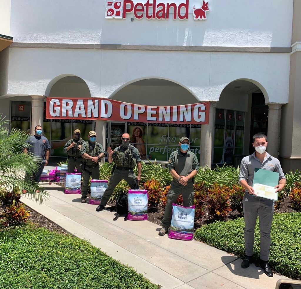 Petland Naples picture of police officers standing with bags of dog food in front of Petland Naples store.
