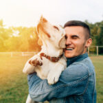 A young man holding his adorable dog.