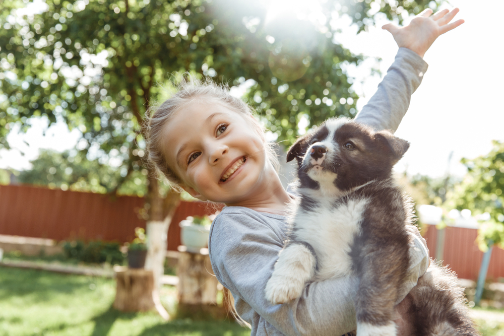 A cute little girl holding her adorable puppy.