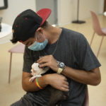A patient from WOW Center Miami petting and cuddling a cute Petland puppy.