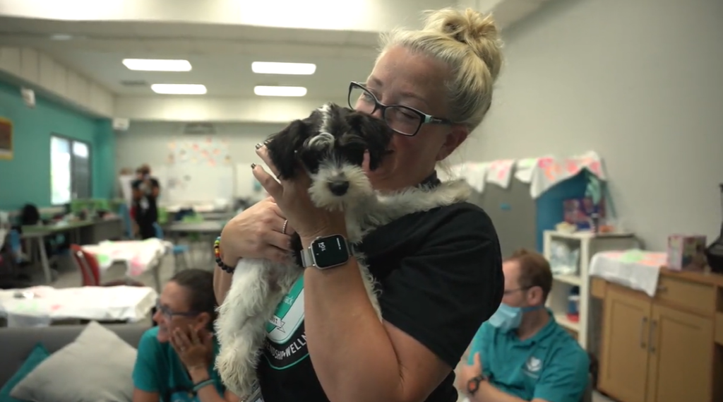 A woman from the David Posnack JCC holds and cuddles a cute puppy from Petland.