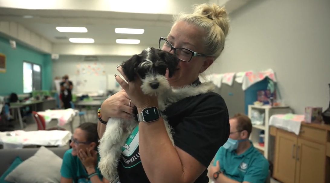 A woman from the David Posnack JCC holds and cuddles a cute puppy from Petland.