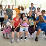 A group of members from the WOW Center sitting on a table outside and cuddling puppies from Petland.