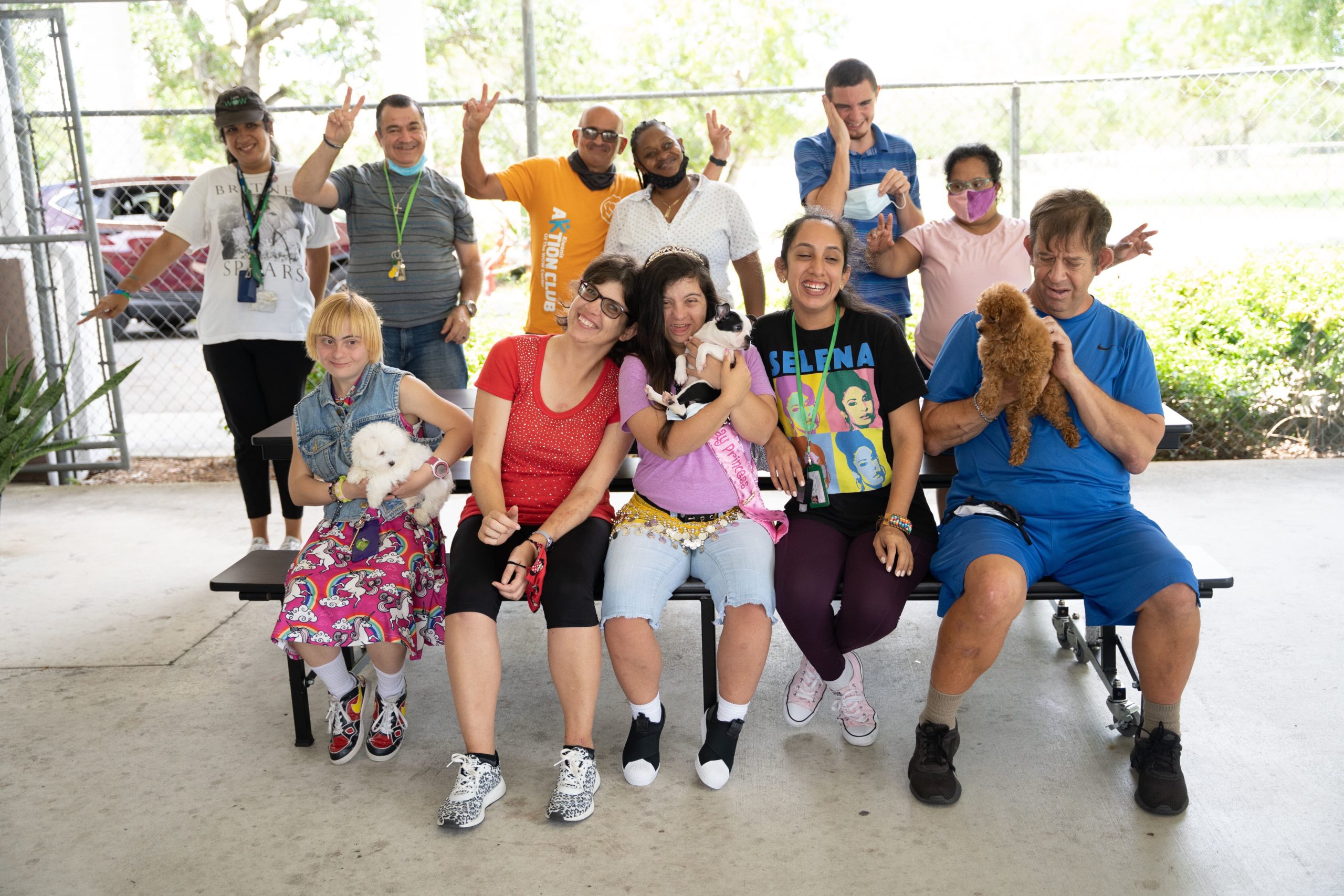 A group of members from the WOW Center sitting on a table outside and cuddling puppies from Petland.