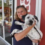 A cute puppy is held by a volunteer from Patriot Service Dogs.